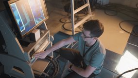 Person adjusting video equipment in TV studio, focused on monitor displaying broadcast setup. Timer on control panel shows time, studio lighting and cables visible in background - Powered by Shutterstock - Get 15% off with code: PIKWIZARD15