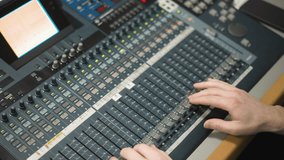 Close-up of broadcast sound mixing desk. Hands adjusting sound levels on faders, professional audio equipment in control room. Audio operator focused on controlling live production sound - Powered by Shutterstock - Get 15% off with code: PIKWIZARD15