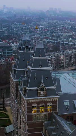 Vertical 4K drone video Rijksmuseum Amsterdam at magical blue hour twilight with glowing windows. Breathtaking aerial footage of Dutch architectural masterpiece perfect for mobile video platforms.