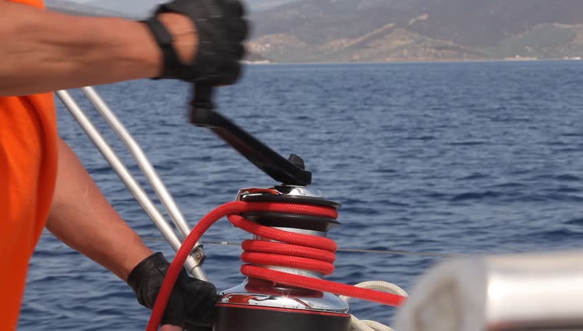 Man sailing (HD), man pulling ropes, winding sheets around winches, shot in full
