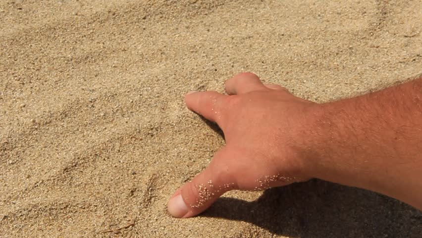 A man grabing sand on the beach with a hand.