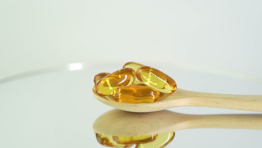 Vitamin capsules in wooden spoon, soft gels, Fish oil capsules, omega 3, oval gelatin, vitamin E