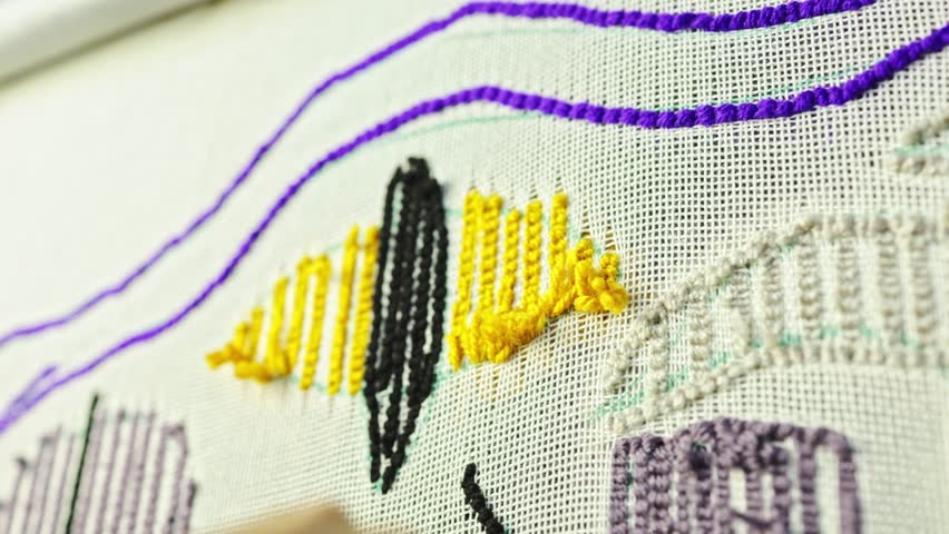 Close up of craftswoman removing threads on carpet canvas