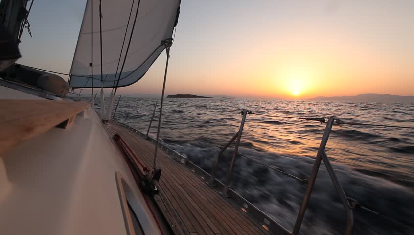 Sailing in the wind through the waves during sunset (HD) Sailing boat shot in