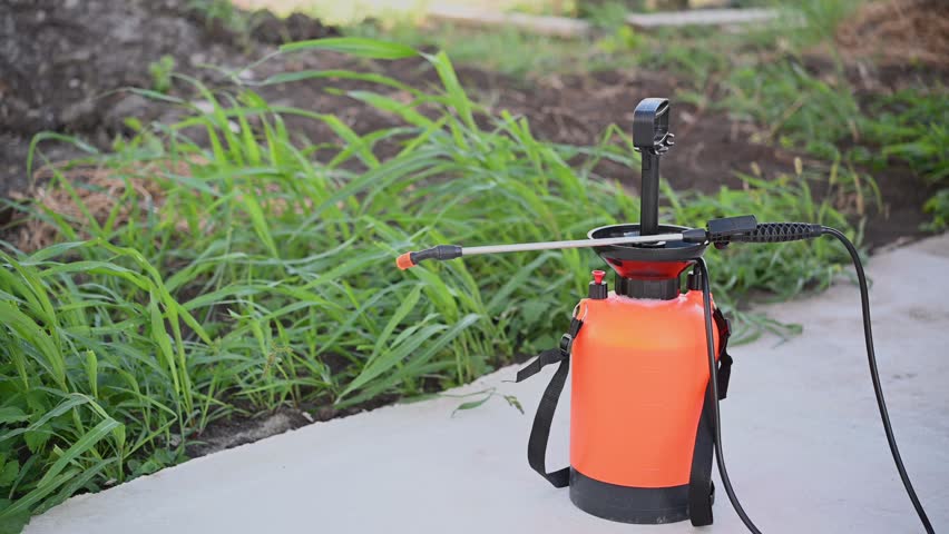 Removing weeds in the garden with liquid chemicals. Cleaning the top layer of soil from plants. Portable lawn and garden sprayer for spraying plants, garden watering, household cleaning.
