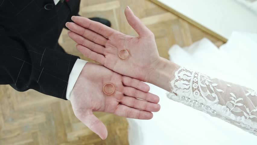 Caucasian couple, hands close up. Rings are in their palms and they are squeezing them at the same time.