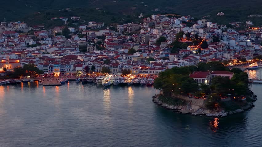 Aerial view of the illuminated old port and Bourtzi island during summer dusk at Skiathos town, Sporades, Greece