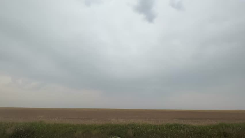 Driving through rural Alberta farmland with wide open agricultural fields, rustic fences, and prairie horizon views showcasing the peaceful countryside and farming lifestyle.