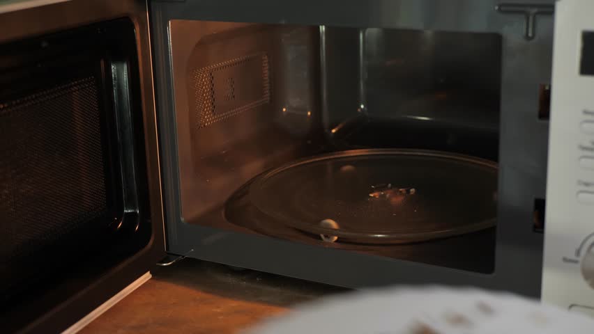 The process of heating food in a microwave oven. Male hand cooks quickly, saving time for food to be heated
