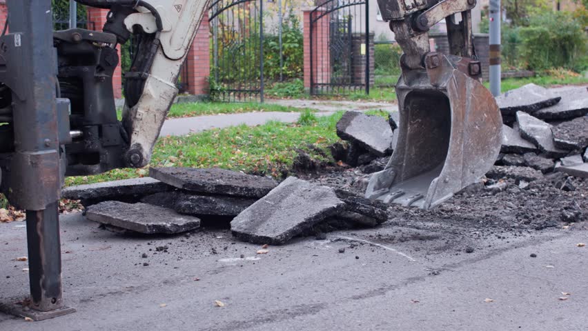 Heavy machinery is excavating asphalt from the street to carry out essential urban repair and maintenance work