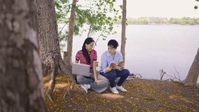 Asian young couple spend time on a romantic date in the outdoors garden. Attractive man and woman feel happy and relax, with one using laptop and the other reading a book while having picnic in park. - Powered by Shutterstock - Get 15% off with code: PIKWIZARD15