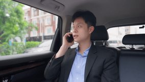 Asian man talking on phone while sitting in the back seat of a car. Attractive young businessman working or checking information remote on smartphone, enjoy business travel during a city commute. - Powered by Shutterstock - Get 15% off with code: PIKWIZARD15