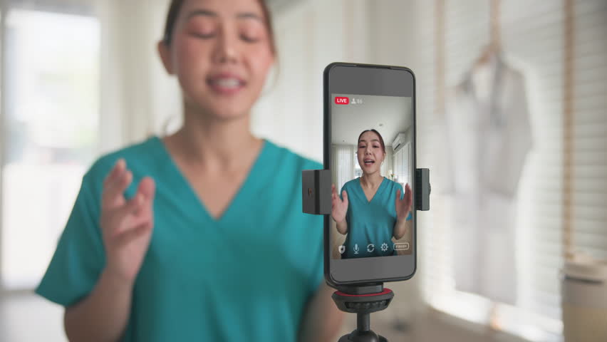 Young adult woman asia Gen Z people anti aging expert modern nurse live talk viral video selfie camera on mobile phone app mental health care. Online sharing digital virtual asian vlogger filming.