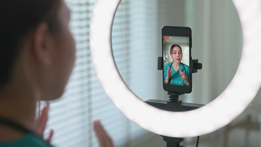 Young adult woman asia Gen Z people anti aging expert modern nurse live talk viral video selfie camera on mobile phone app mental health care. Online sharing digital virtual asian vlogger filming.