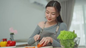 Young woman in casual clothing preparing fresh vegetables in a modern kitchen, focusing on healthy meal preparation and culinary skills - Powered by Shutterstock - Get 15% off with code: PIKWIZARD15