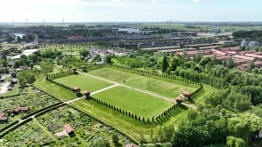 Aerial semi orbit highlighting Matilo green field, framed by trees and urban surroundings in the Netherlands.