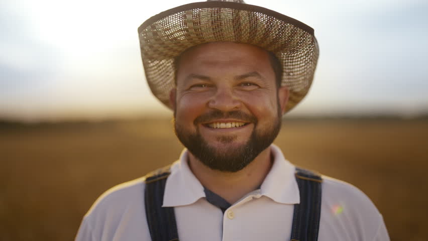 Portrait of successful farmer in agricultural fields, smiling to camera. Beautiful nature of rural area, happy face of middle-aged farm worker or agronomist in golden farmland, growing cereals