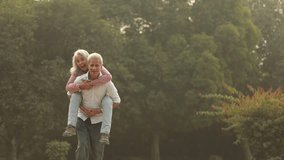 A happy couple shares joyful laughter as the man gives a playful piggyback ride to his partner in a sunny outdoor park. - Powered by Shutterstock - Get 15% off with code: PIKWIZARD15