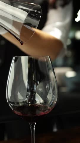 Red wine in a transparent decanter. Slow motion video, close-up. The bartender prepares wine for consumption.
