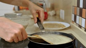 Woman chef is skillfully flipping a thin pancake in a non-stick frying pan, using a wooden spatula, creating a delicious breakfast in a modern kitchen - Powered by Shutterstock - Get 15% off with code: PIKWIZARD15