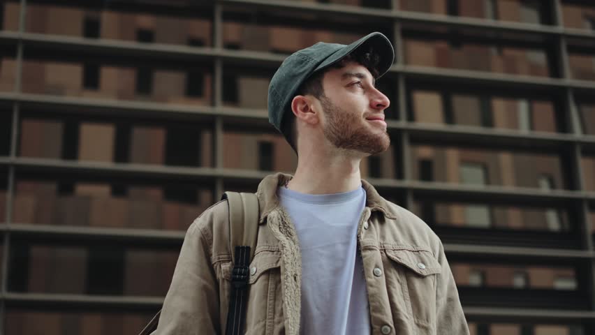 Young man wearing cap looking the city with confident expression - Professional aspirations and inspiration