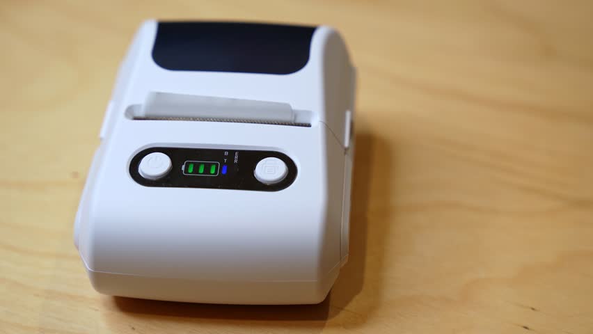 Close-up of compact thermal printer printing Arabic text “Only With Us” on receipt paper in a modern business setting.