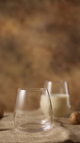 Woman pours Potato milk alternative non dairy drink in glass from decanter on sackcloth. Healthy vegetarian and vegan drink concept FullHD footage vertical video