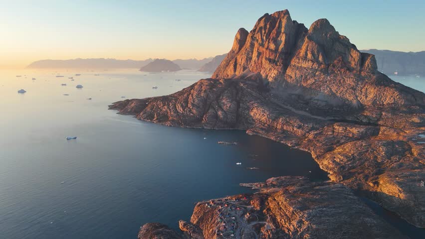 Town Uummannaq during summer in northern West Greenland beyond the Arctic Circle. Greenland, Danish territory. Large mountains and glaciers in the background. Misty morning. Fjord in Greenland. Aerial