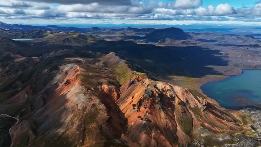 Aerial drone view of Landmannalaugar in Iceland with colorful rhyolite mountains with blue lake, and scenic highlands.