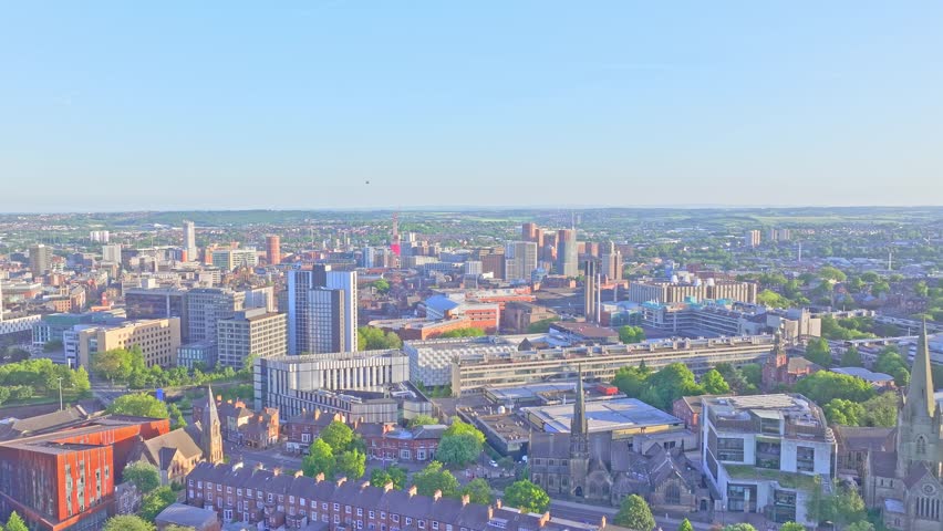 Aerial view of Leeds, England, UK, on a clear sunny day, showing modern buildings, green spaces, and expansive cityscape.
