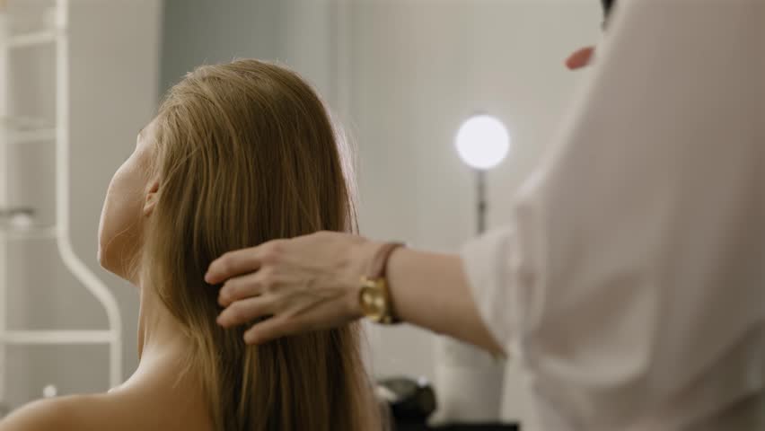 Female makeup artist hairdresser spraying hairspray on model hair. Close-up