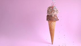 summer funny creative concept of standing wafer cone with chocolate and chocolate chips scoops of ice cream decorated with strewed sprinkles on pink background, copy space, slow motion - Powered by Shutterstock - Get 15% off with code: PIKWIZARD15