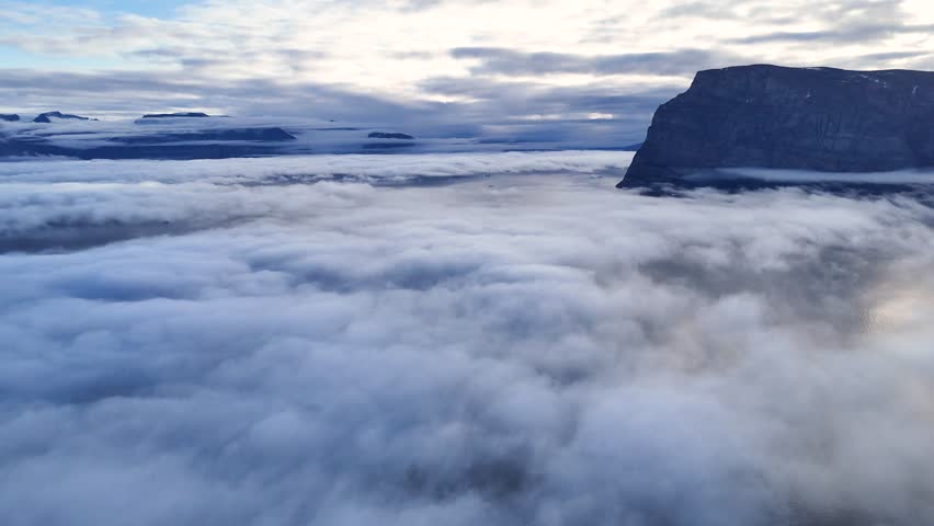 Town Uummannaq during summer in northern West Greenland beyond the Arctic Circle. Greenland, Danish territory. Large mountains and glaciers in the background. Misty morning. Fjord in Greenland. Aerial