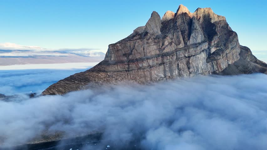 Town Uummannaq during summer in northern West Greenland beyond the Arctic Circle. Greenland, Danish territory. Large mountains and glaciers in the background. Misty morning. Fjord in Greenland. Aerial