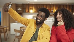 Man in yellow shirt taking selfie with smartphone while woman in red sweater laughs, sitting at cafe table. African American male and curly-haired female enjoying coffee and fun moment together indoor - Powered by Shutterstock - Get 15% off with code: PIKWIZARD15