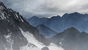 Layered mountain ridges emerging through mist and snow, snow-capped peaks shrouded in dramatic clouds and haze - Powered by Shutterstock - Get 15% off with code: PIKWIZARD15