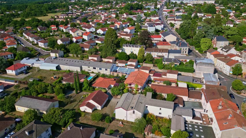 Aerial perspective revealing Saint Junien's residential landscape, featuring red roofed homes nestled among verdant trees and meticulously planned urban spaces