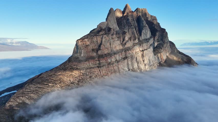 Town Uummannaq during summer in northern West Greenland beyond the Arctic Circle. Greenland, Danish territory. Large mountains and glaciers in the background. Misty morning. Fjord in Greenland. Aerial