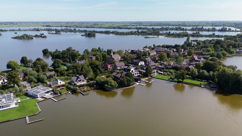 Aerial view of a lakeside residential area with private docks, green lawns, and calm water. The layout reflects a peaceful community adapted to waterfront living and recreational access.