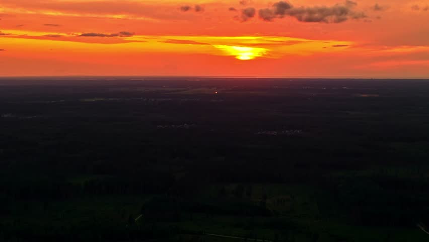 Beautiful sunset casting orange glow over forest landscape in aerial panorama