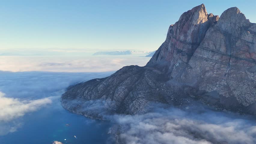 Town Uummannaq during summer in northern West Greenland beyond the Arctic Circle. Greenland, Danish territory. Large mountains and glaciers in the background. Misty morning. Fjord in Greenland. Aerial
