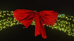 Red Christmas bow gently sways in the wind above glowing festive garlands - Powered by Shutterstock - Get 15% off with code: PIKWIZARD15