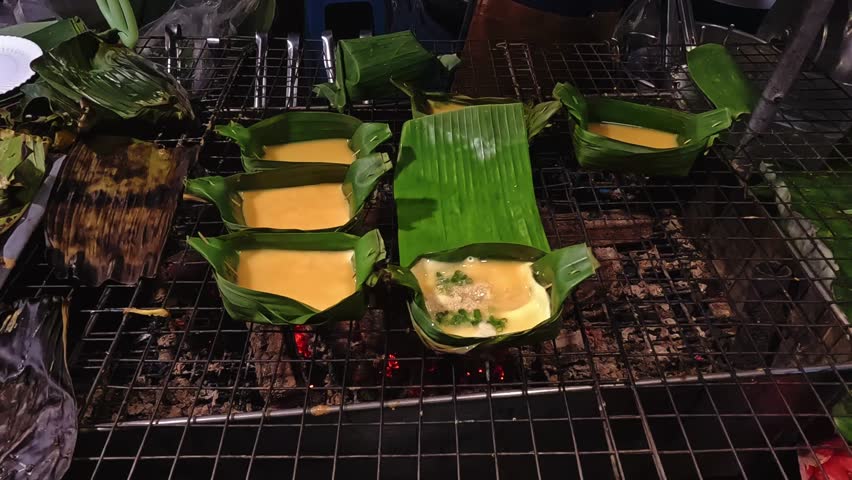 Hands preparing to grill eggs in banana leaves which is an authentic local thai street food called Kai Pam from Chiang rai, Thailand