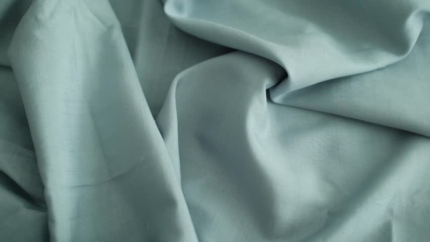 Closeup video of hands touching soft blue silk fabric. Appreciating pleasant texture of high quality textile for clothes. Soft and cozy textile. Premium quality silk fabric for luxury clothes.