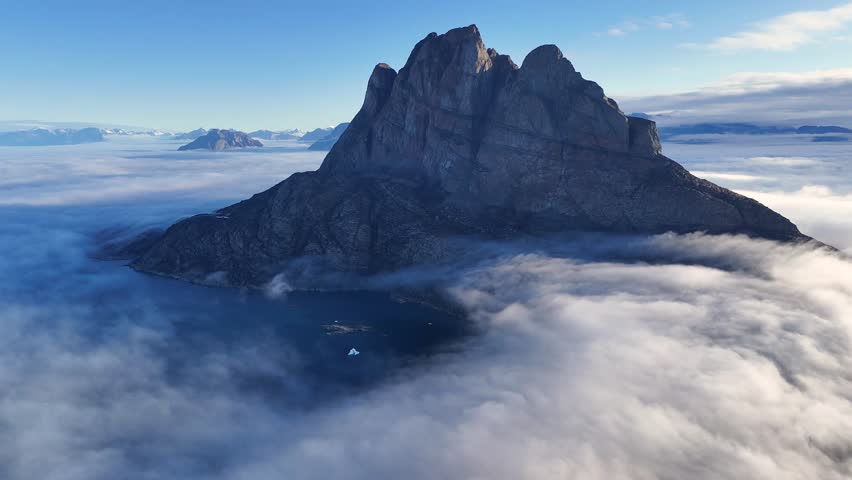 Town Uummannaq during summer in northern West Greenland beyond the Arctic Circle. Greenland, Danish territory. Large mountains and glaciers in the background. Misty morning. Fjord in Greenland. Aerial