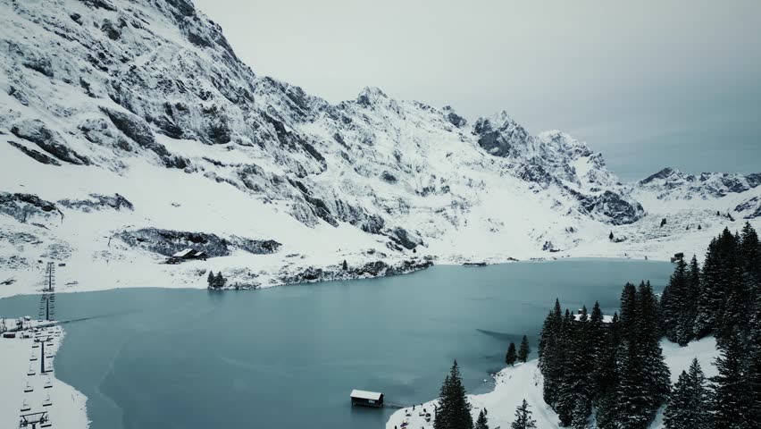 Aerial drone view of Trubsee lake in winter in Engelberg, Switzerland. Picturesque view of Titlis mountain in Swiss Alps covered in snow