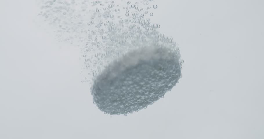 Extreme Close-up effervescent tablet, pill bubbling underwater. Shot on super slow motion camera 1000 fps.