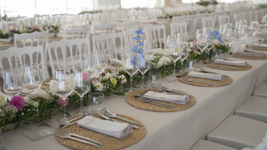 Elegant wedding banquet setup with flowers plates and glassware in bright hall