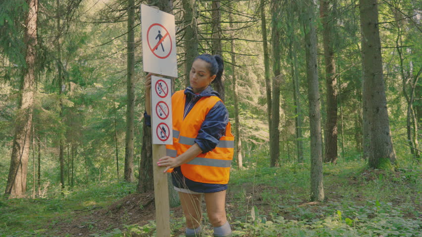 Cute woman is fix the warning sign in the park