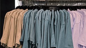 Multiple blue and lilac cotton t shirts hanging on black hangers arranged in row inside clothing retail store wardrobe section - Powered by Shutterstock - Get 15% off with code: PIKWIZARD15